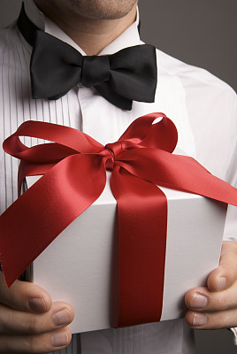 男人在黑色领结持有豪华礼品红色蝴蝶结图片下载