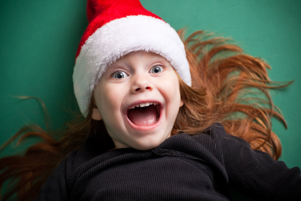 兴奋的女孩戴着圣诞老人的帽子和微笑图片下载