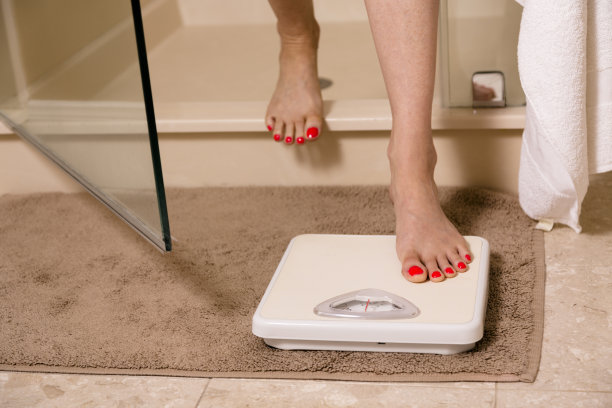 健康生活方式:减肥。女人从淋浴间出来。规模。图片下载