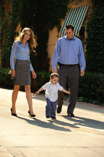 阳光明媚的一天，年轻的父母带着蹒跚学步的孩子散步图片下载