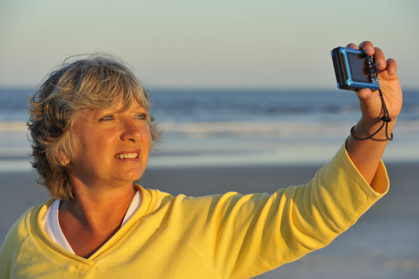 一个在海滩上自拍的女人，在度假的时候拍照图片下载