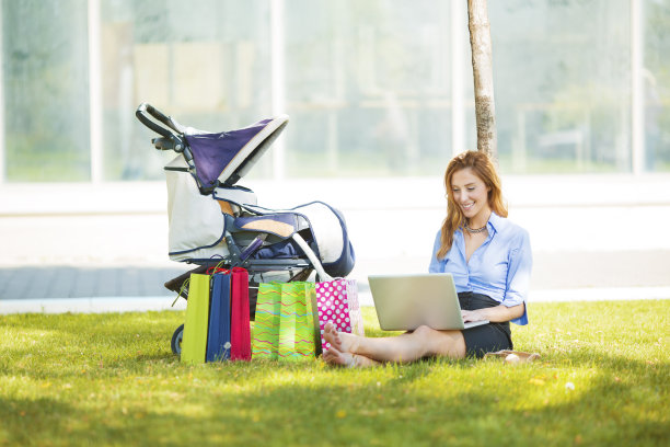 在公园里推着婴儿车的快乐的商业母亲图片下载