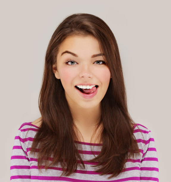 扮鬼脸。美丽的年轻女子伸出舌头图片下载