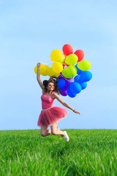 穿着礼服的年轻女子拿着一堆气球跳来跳去图片下载