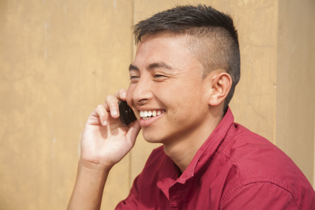 快乐的亚裔男人在户外用智能手机聊天。图片下载