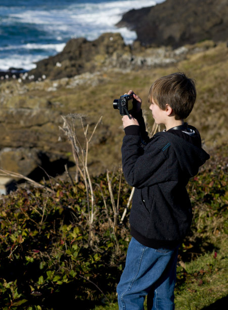 年轻的摄影师正在拍摄海岸，海洋的照片图片下载
