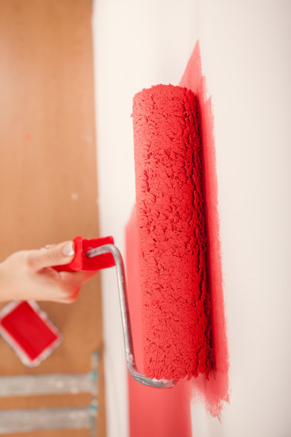 白色墙壁上的红漆滚轮图片下载