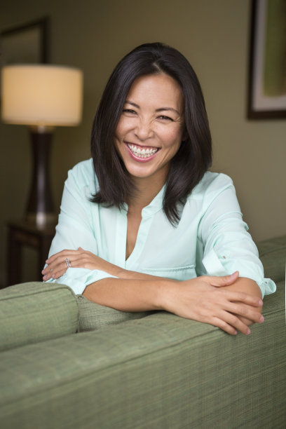美丽的亚洲女人坐在沙发上微笑图片下载