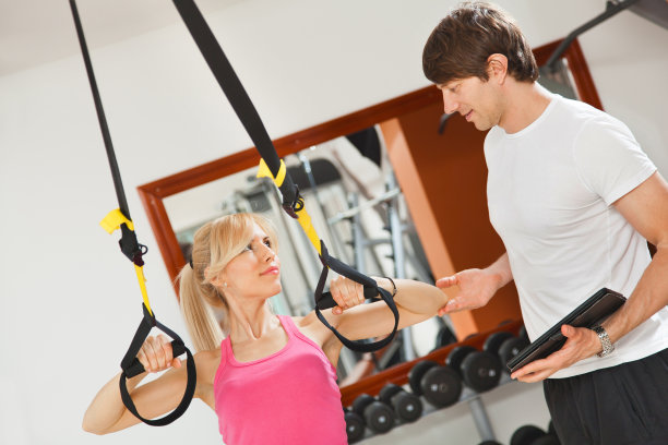 在健身房用悬挂健身带锻炼的女人。图片下载