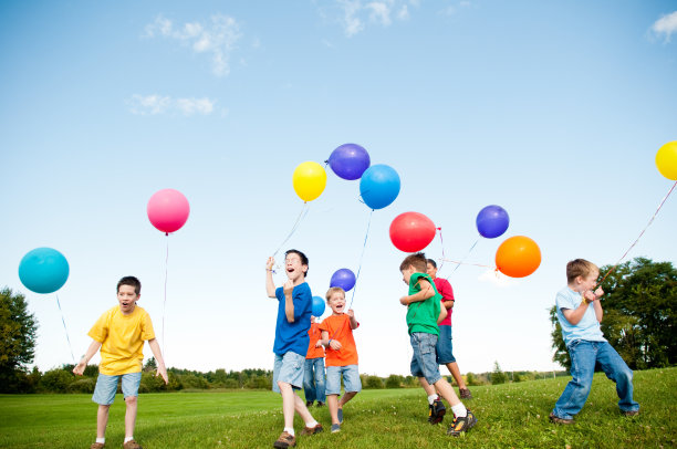 一群兴奋的男孩拿着气球在外面跳着、喊着图片下载
