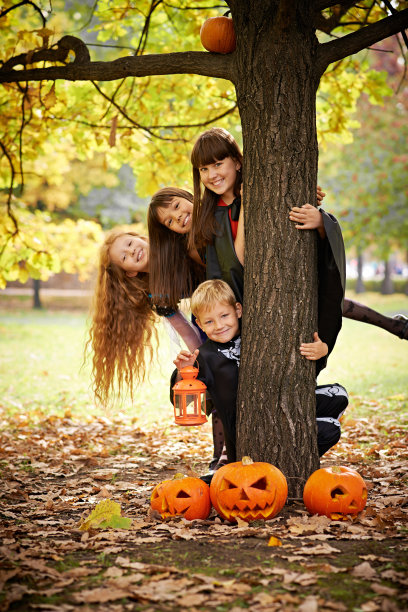 万圣节前夕，顽皮的孩子们躲在树后面图片下载