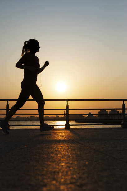 剪影的女人与马尾辫慢跑在金色的太阳图片下载