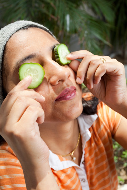 印度女孩与黄瓜放置在她的眼睛美容治疗图片下载