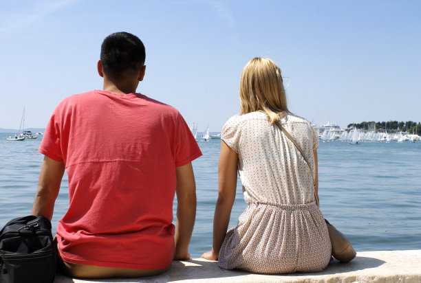 一对年轻英俊的夫妇坐在海边图片下载