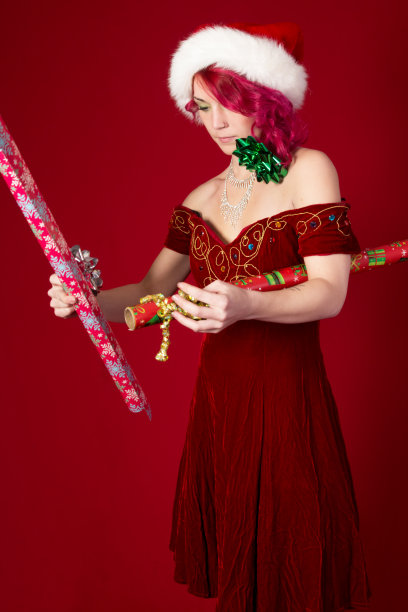 圣诞精灵困惑地看着纸和蝴蝶结。图片下载