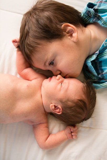 蹒跚学步的小男孩亲吻刚出生的弟弟图片下载