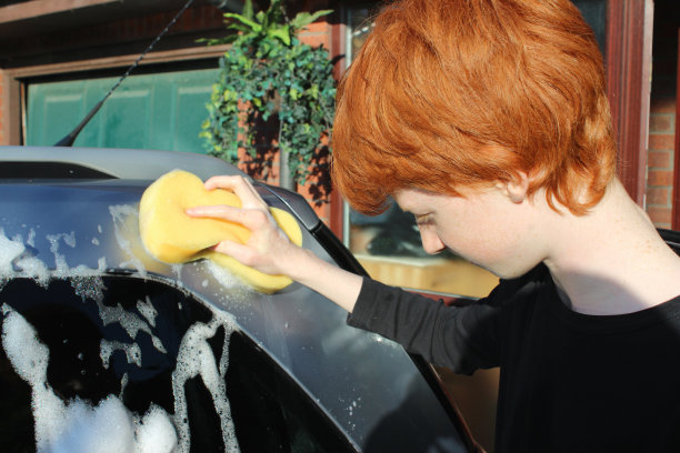 十几岁的男孩用海绵/洗车器洗车窗图片下载