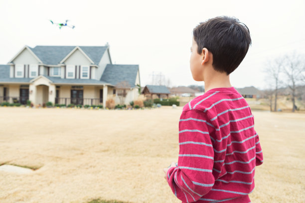 小男孩在前院玩四轴飞行器图片下载