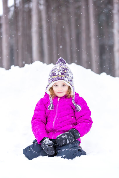 年轻女孩坐在雪堆前在冬天图片下载