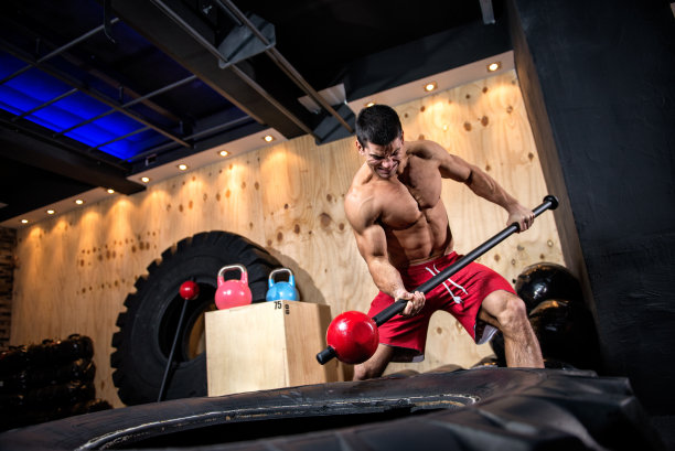 男健身运动员敲打着巨大的轮胎图片下载