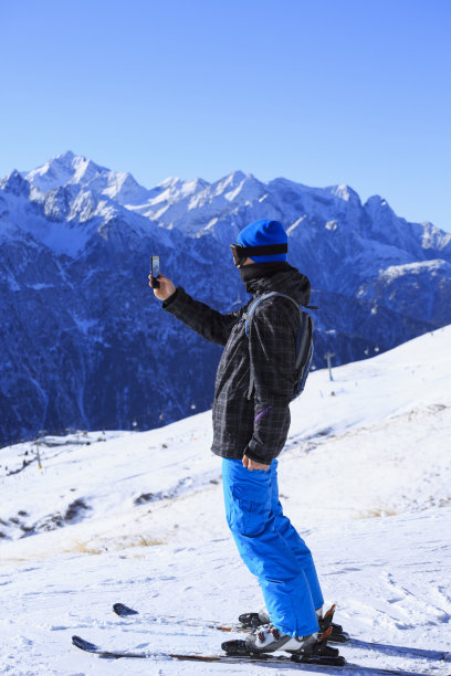 滑雪少年用触屏智能手机拍摄冬季风景图片下载