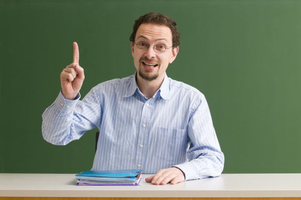 老师坐在桌前指指点点图片下载