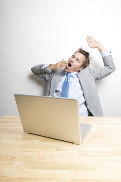 一个办公室职员从他的办公桌向后靠，打了个大哈欠图片下载