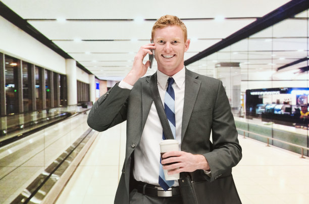 微笑的商人在机场用手机交谈图片下载