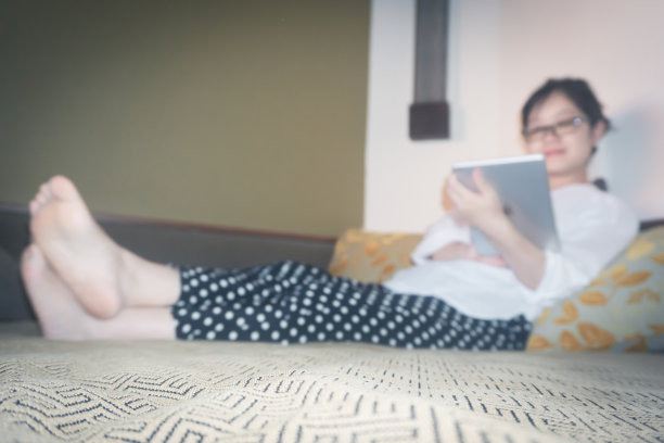 美丽的女人在榻榻米沙发上使用数码平板电脑图片下载