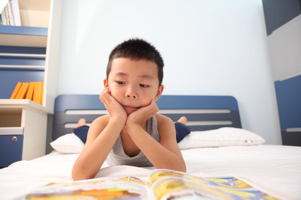 亚洲男孩在床上看书图片下载
