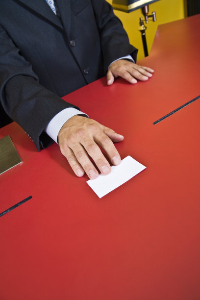 拿着卡片坐在办公桌前的人[靠近]图片下载