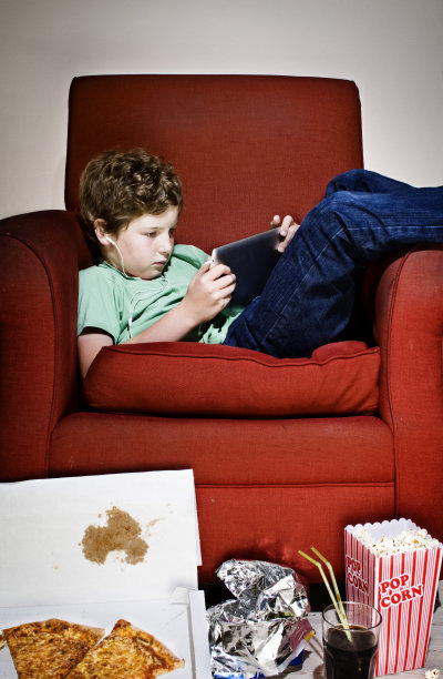沙发土豆男孩被垃圾食品包围着玩电脑游戏图片下载