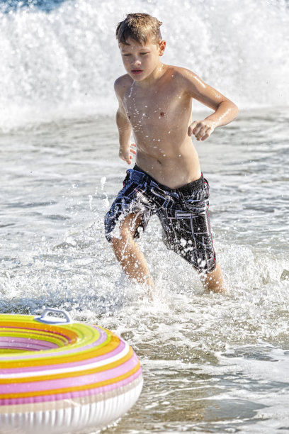 男孩享受在冲浪追逐他的内胎一天图片下载