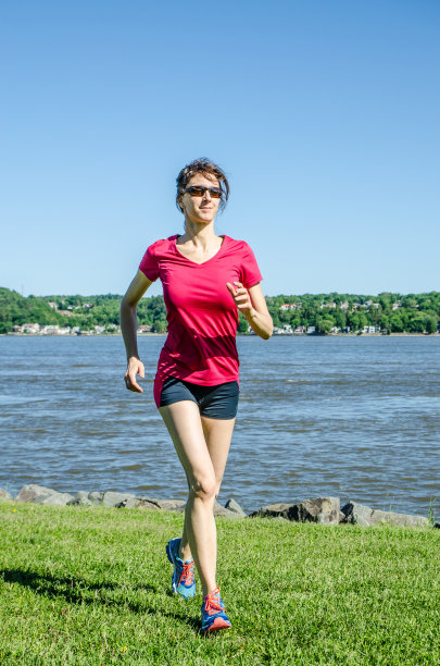 在河边草地上慢跑的女人图片下载