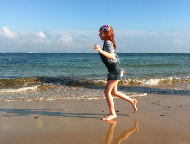 一个红头发的女孩在沙滩上玩耍图片下载