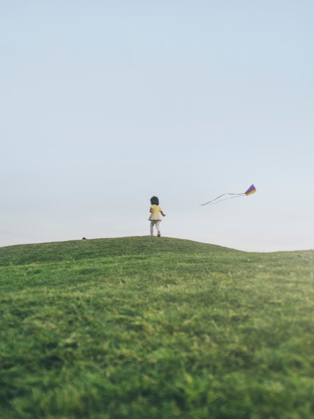 一个亚洲小女孩在草坪上跑去放风筝图片下载