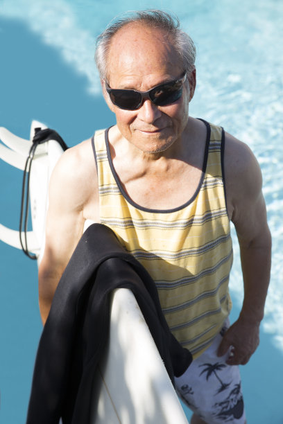 高级冲浪者拿着冲浪板，背景是水图片下载