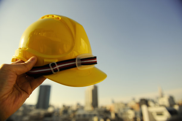 在晴朗的天空下，拿着黄色的安全帽图片下载