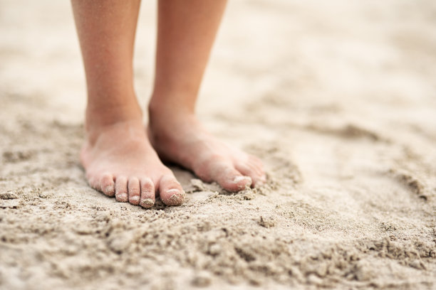 孩子的脚踩在沙滩上图片下载