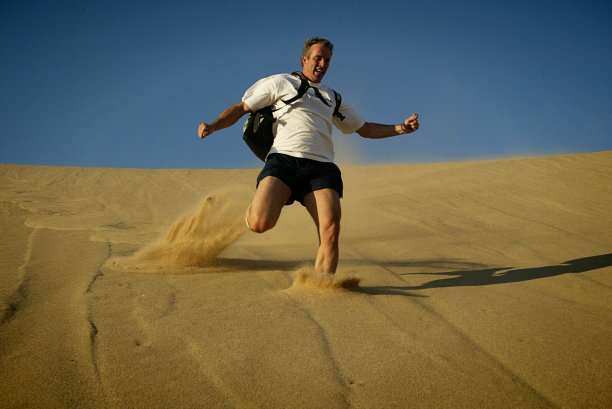 男人跑下陡峭的沙丘图片下载