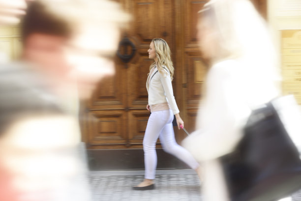 运动模糊时尚的女人与手袋在人群中行走图片下载