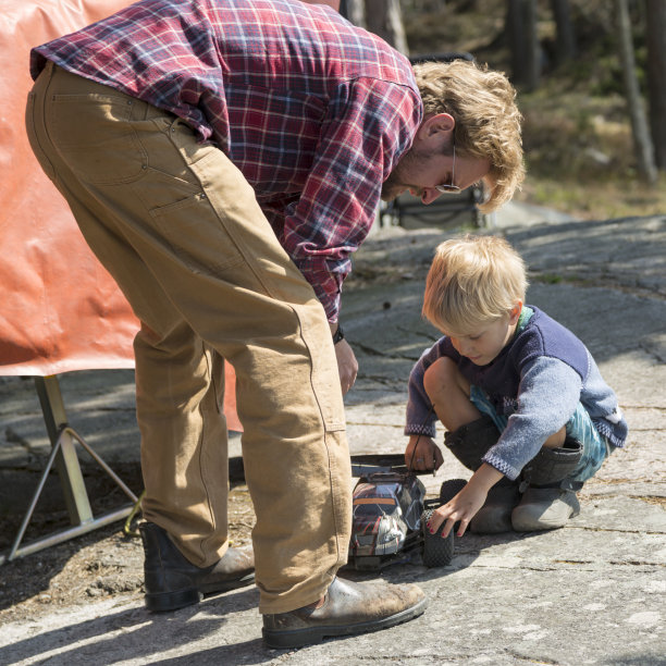 父亲看着小儿子玩汽车。图片下载
