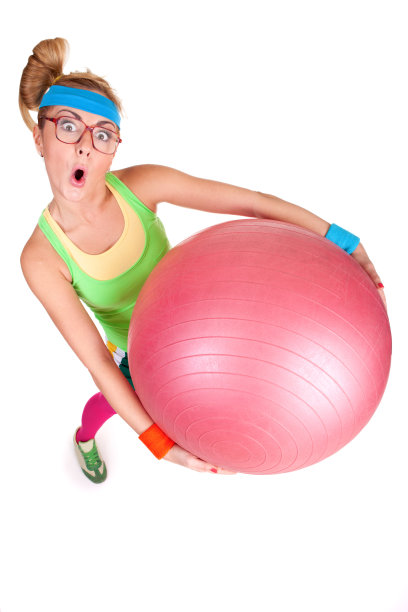 书呆子女孩做鬼脸，拿着粉色健身球图片下载
