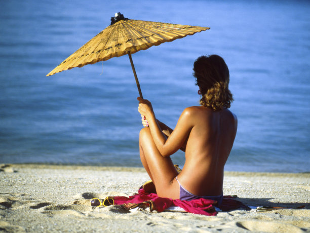 在海滩上打着伞的女士。泰国。图片下载