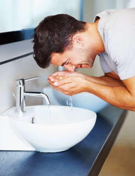 一位中年男子在浴室里洗脸图片下载