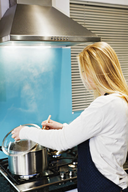 金发女人在检查炉子上煮的锅冒热气的内容图片下载