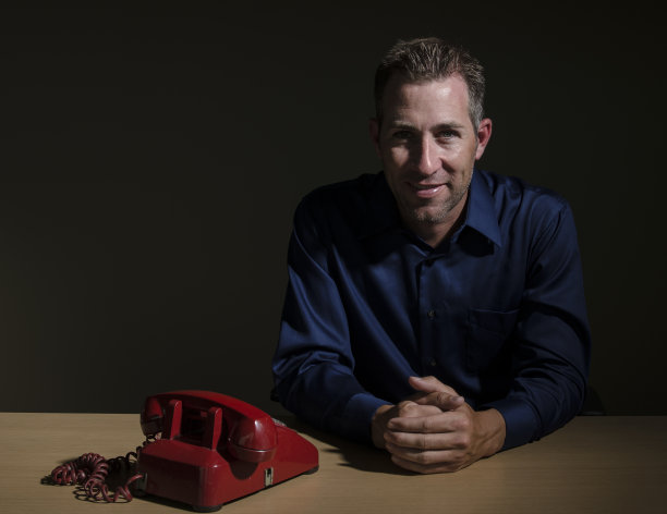 微笑的商人与红色座机电话图片下载