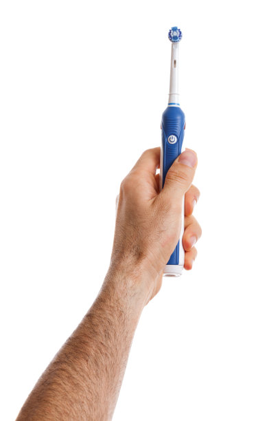 手里拿着电动牙刷的男人。图片下载