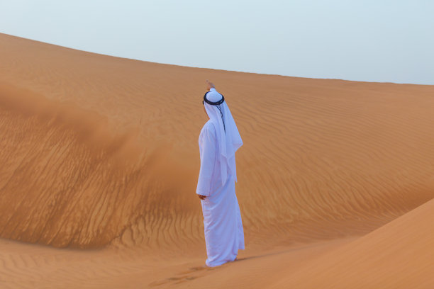 在迪拜沙漠中指路的阿拉伯人图片下载