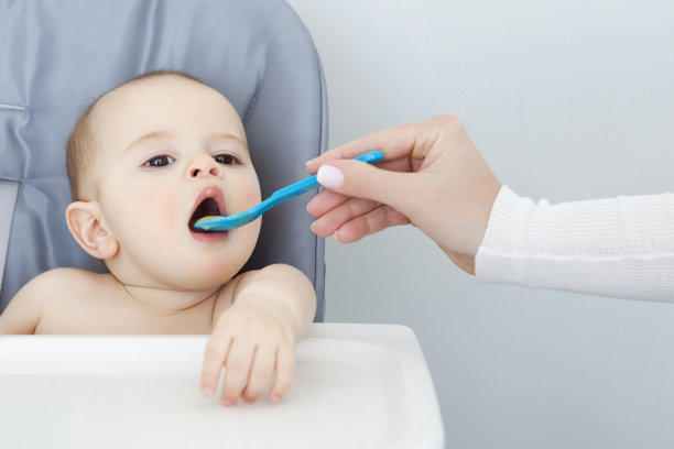 小男孩在他的椅子上吃妈妈的手素材图片